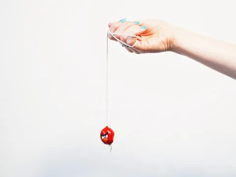 A hand holding a lace, with a painted conker hanging from it.