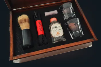 The open Gentleman's Conker Kit: a brush, a black lace, a bottle of Conker Gin and two glasses in a fitted wooden box.