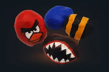 Four painted conkers: one red with an angry face, one blue, one striped black and yellow, and one with a toothed mouth.