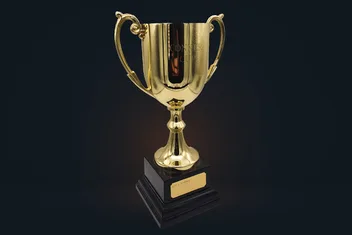 The Conker Cup trophy on a dark studio floor: a gold cup on a black plinth with a brass plaque.